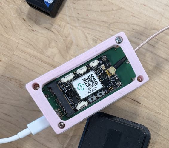 PointOneNav GPS board in a pink enclosure connected to a black magnetic patch antenna via a coaxial SMA cable